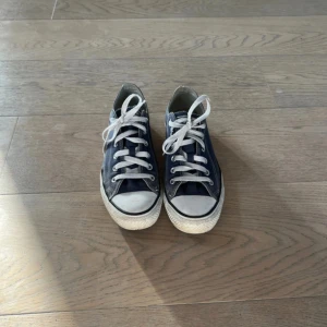 Mörkblå Converse All Star sneakers - Klassiska mörkblå Converse All Star sneakers med vit sula och vita snören. Skorna har rund tå, platt sula och är tillverkade i canvas med gummidetaljer. Perfekta för en avslappnad och cool stil.