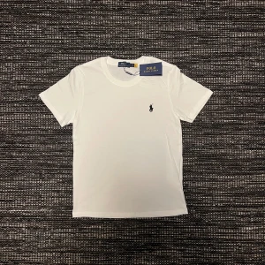 Helt ny vit t-shirt från Polo Ralph Lauren - Vit t-shirt från Polo Ralph Lauren med klassisk rund hals och korta ärmar. T-shirten har den ikoniska broderade loggan på bröstet och är gjord i mjuk bomull för en clean och stilren look. Priset kan diskuteras. 