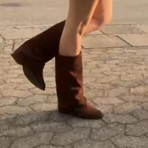 Bruna mocka boots - Säljer ett par snygga bruna boots i mocka med spetsig tå och låg klack. Skorna har en klassisk western-vibe och passar perfekt till både jeans och klänning. De har en mörkbrun färg och en stilren design som sticker ut.