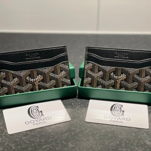  plånbok med ikoniskt mönster - Snygg och exklusiv plånbok från  i svart med klassiskt grafiskt mönster i vitt och brunt. Insidan är gul och plånboken har flera kortfack. Perfekt för dig som vill ha något unikt och stilrent i fickan. 1 för 200 2 för 350