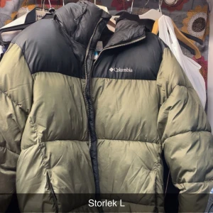 Columbia pufferjacka i svart och olivgrön - Säljer en fet pufferjacka från Columbia i olivgrönt med svarta axlar och bröst. Jackan har hög krage, dragkedja och synligt logotryck på bröstet. Perfekt för kalla dagar och har en riktigt chill oversized vibe.