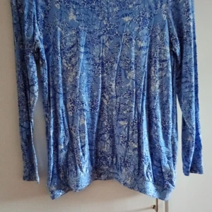 Blå långärmad topp från Esmara - Säljer en blå långärmad topp från Esmara med ett snyggt blommigt mönster i olika blå nyanser och vitt. Materialet är mjuk och skön viskos med lite elastan för extra komfort. Perfekt för dig som gillar färg och mönster!