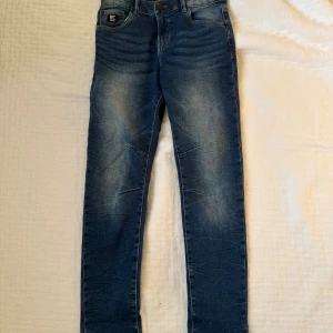 Blå jeans från LAB Industries, stl 158 - Snygga blå jeans från LAB Industries i klassisk denim med slitningar och ljusare partier framtill och baktill. Modellen har raka ben, fem fickor och kontrastsömmar.