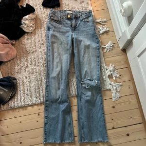 Ljusblå jeans från Ginatricot. - Säljer ett par ljusblå bootcut midwaist jeans från ginatricot i storlek 32. Har ett hål i högra knät som ska vara så.