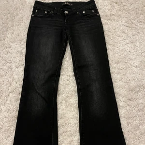 Svarta bootcut jeans med nitar - Snygga svarta jeans med bootcut passform från G-Rise. Jeansen har dekorativa nitar på bakfickorna och klassisk femficksdesign. Använt några gånger. Mycket bra skick förutom att det lossnat några stenar på backfickorna, Innerbenslängd- 77 cm