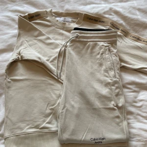 Calvin Klein mjukis-set  - Snyggt mjukis-set från Calvin Klein med logga på ärmarna. Både tröja och byxa är i fint skick, inga defekter eller liknande. Perfekt för en chill och stilren look.
