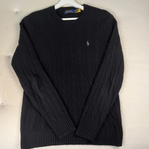 Kabelstickad ull-kashmir tröja Polo Ralph Lauren - Snygg svart kabelstickad raffe tröja. Ull och kashmir blend. Jag är 184 och passformen är slim. Nypris ligger på 2695kr. Tröjan är lite nopprig på vissa ställen men inga större defekter. Hör gärna av er vid frågor! 🙌🙌