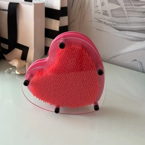 Hjärta Pin Art 3D - Unik hjärtformad Pin Art 3D med röda plastnålar och transparent ram. Skapa roliga 3D-avtryck av händer, ansikten eller föremål. Produkten är i mycket gott skick utan synligt slitage eller defekter. Perfekt som dekorativ pryl eller kreativ leksak.