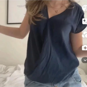 Mörkblå blus med v-ringning - Säljer en stilren mörkblå blus med v-ringad hals och korta ärmar. Blusen har en loose passform och är tillverkad i ett mjukt, lätt material som ger en skön känsla. 