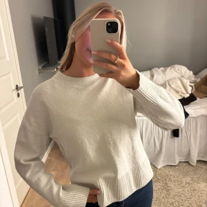 Vit stickad tröja från &other stories  - Säljer en stilren vit stickad tröja med rund hals och långa ärmar. Tröjan har breda ribbade muddar vid ärmslut och nederkant som ger en snygg detalj. Passformen är normal och materialet känns mjukt och skönt mot huden. Perfekt att matcha med jeans. Tröjan är nopprig men den funkar fof jättefint.