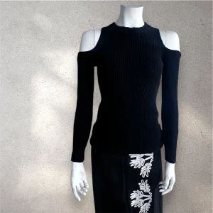 Gina Tricot  stickad  tröja - Svarte stickad tröja från Gina Tricot  med ribbad struktur och snygg offshoulder-design som visar axlarna. Tröjan har lång ärm och en rundad halsringning. Passformen är slim och materialet känns mjukt och följsamt mot kroppen. Perfekt för dig som gillar en stilren och trendig look. #ginatricot #tröja