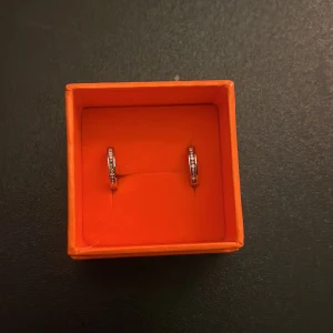 Silverfärgade örhängen med stenar - Säljer ett par stilrena silverfärgade örhängen med små rosa stenar. 