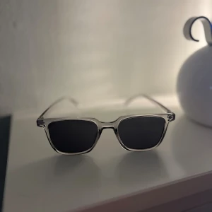 Castello Glasögon - Snygga solglasögon med transparent båge och svarta rektangulära glas. De är i ett nytt skick imed att de bara legat i lådan och har aldrig använts. Jättesnygga glasögon för övrigt. Hör av er om ni har frågor!