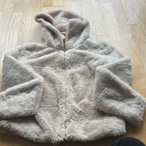 Beige teddyjacka med huva från ONLY - Mysig teddyjacka i beige från ONLY, storlek S. Jackan har huva, lång ärm och en stor rund dragkedja framtill med metallring. Utsidan är fluffig och mjuk, insidan är slät och ljus. Perfekt för dig som gillar chill och comfy vibes. Det är inga fläckar och inga skador på jackan!!❤️