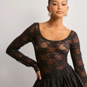 Svart spetsblus med lång ärm - Säljer en svart, transparent spetsblus från Nelly med lång ärm och rundad halsringning. Blusen har ett blommigt spetsmönster och en liten rosett framtill. Väldigt snygg passform. Aldrig använd 🩷