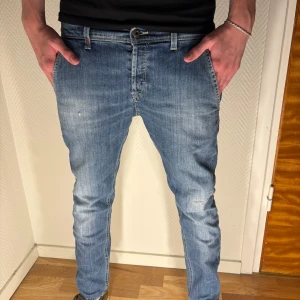 Dondup jeans George - Säljer ett par blå jeans med snygg tvätt och klassiska detaljer. Jeansen har normal midja, raka ben med lätt avsmalnande passform och fem fickor. Materialet är mjukt denim i bomull och de har en stilren look som passar till det mesta. Storlek 32 (sitter som 30)