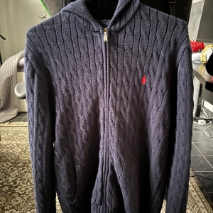 Mörkblå stickad hoodie från Polo Ralph Lauren - Tjena Säljer en mörkblå stickad zip hoodie nästan som en cardigan från Polo Ralph Lauren den är lite för stor för mig bara vid armarna därför jag vigt dom på bilden är 172, köpte för 1500 kr från Zalando storlek xl i barn 18-20 använt en gång men märkte den var lite för stor därför jag säljer skick 10/10 mitt pris 1200 för den är helt ny men priset kan absolut diskuteras vid fundering är de bara höra av sig🙌🏼 