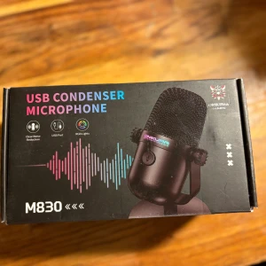Onikuma M830 USB Condenser Microphone - Onikuma M830 är en USB-kondensatormikrofon med tydlig brusreducering, RGB-belysning och enkel USB-anslutning. Perfekt för streaming, gaming och inspelning. Produkten är i nyskick i originalförpackning.