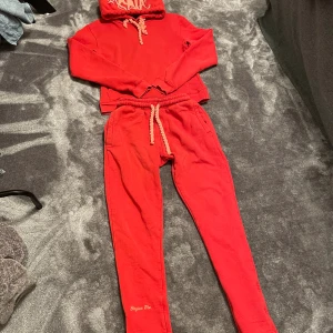 Central cee Syna World tracksuit - Röda mjukisbyxor med resår och grovt snöre i midjan. Byxorna har broderad text 'Forgive Me' vid benet och är tillverkade i mjukt bomullsmaterial. Perfekta för chill dagar och streetwear-vibe.