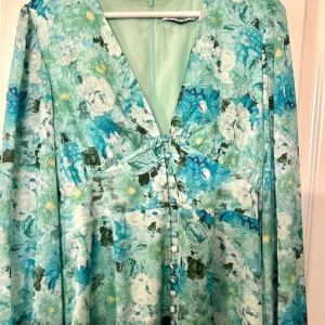 Positano Dress, Adoore - Fin lång sommarklänning i ett blommigt mönster. Positano dress från Adoore i färgen mint Green. Endast använd en kvälln så inga skador eller slitningar. Storlek 42, men då jag upplever Adoores storlekar ganska små så skulle jag säga att den även passar en storlek 40. 