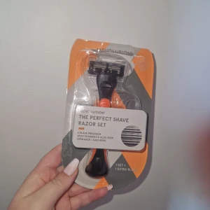 Rakhyvel - Revolution The Perfect Shave Razor Set för män med 6-bladsprecision, vitamin E och aloe strip. Den är helt oanvänd men förpackningen har synliga revor samt några ritningar på baksidan. Inkluderar 1 rakhyvel och 1 extra blad.