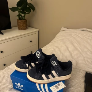 Adidas Campus mörkblå sneakers mocka - Adidas Campus sneakers i mörkblå mocka. Nypris 1449kr, knappt använda därav priset. Både kartong samt vita snören följer med (valfritt). Superbra skick. Storlek 38 (2/3)