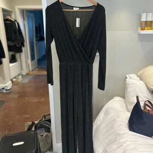 Svart glittrig långklänning Kappahl - Använd en kväll men syns inte. Supersnygg svart långklänning från Kappahl med glittrigt tyg och omlott-v-ringning. Klänningen har långa ärmar och markerad midja, perfekt för att sticka ut. Materialet är mjukt och stretchigt syntet. Säljes i storlek 158. Men passa även xs den är stretchig. 🥰🥰