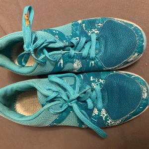 Turkosa sneakers med mönster - Snygga turkosa sneakers med coolt vitt mönster och meshdetaljer. Skorna har snörning och platt sula, perfekta för dig som gillar sportig stil. Lätta och bekväma med fräsch färg som sticker ut.