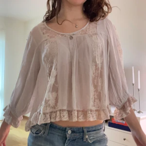 Ljusrosa blus med spets och volang - Säljer en superfin ljusrosa blus med spets. Blusen har volangkant nedtill och vid ärmslut, samt en liten knapp framtill. Den är loose fit och har trekvartsärmar. 