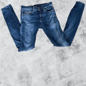 Blå Replay slim jeans  - Snygga blå jeans från Replay med klassisk femficksdesign och guldfärgat broderi på bakfickorna. Jeansen har smal passform och är tillverkade i mjukt denimtyg med lätt slitning för en cool look. Perfekta för dig som gillar stilrena och bekväma jeans.
