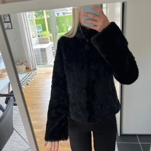 Svart pälsjacka från Zoul - Säljer en svart pälsjacka från Zoul i storlek 34. Jackan har en mjuk och fluffig yta, raka långa ärmar och en klassisk krage. Insidan är quiltad för extra komfort. Perfekt för dig som vill ha en snygg och varm jacka med stil.