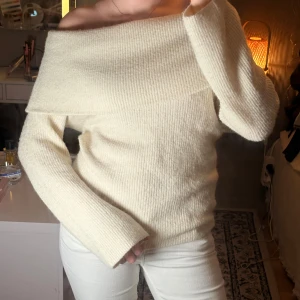 Offshoulder stickad tröja  - Superfin offshoulder stickad tröja från H&M i en ljus cremevit färg. Tröjan har ribbad struktur, lång ärm och bred krage som sitter snyggt över axlarna. Perfekt för dig som gillar en stilren och mysig look.