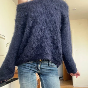 Mörkblå fluffig stickad tröja - Säljer en mörkblå stickad tröja med fluffig yta och diskret mönster. Materialet är mjukt och värmande, passar dig som vill ha en mysig vibe.
