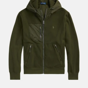 Grön fleece hoodie från Polo Ralph Lauren - Snygg mörkgrön hoodie i fleece från Polo Ralph Lauren med huva och dragkedja framtill. Tröjan har tre praktiska fickor med dragkedja och en broderad logga på bröstet. Perfekt för kyliga dagar och har en normal passform.