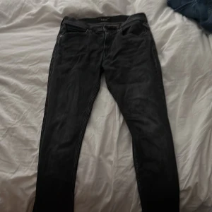 Svarta Replay jeans, storlek 16A - Svarta jeans från Replay med klassisk femficksdesign och snygga slitningar. Jeansen har normal passform och raka ben, tillverkade i ett mjukt jeanstyg som sitter skönt. Perfekta för dig som gillar en stilren och tidlös look.