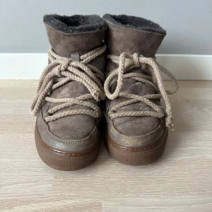 Bruna Inuikii boots med snörning - Säljer ett par bruna Inuikii boots med grov snörning och mjuk pälsfodring. Platt sula och är tillverkade i mocka och skinn. Perfekta för kalla dagar med sin varma insida och snygga design.  Pris kan diskuteras. 