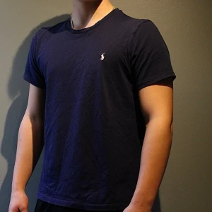 Mörkblå t-shirt från Ralph Lauren - Snygg mörkblå t-shirt från Ralph Lauren med klassisk vit broderad logga på bröstet. Storleken är M men sitter mer som S🙌🏼 bara att höra av dig vid minsta lilla fundering