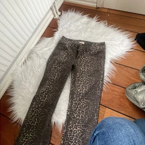 Leopardmönstrade byxor från Nelly - Snygga byxor från Nelly med leopardmönster i bruna och beige toner. Modellen har klassisk femficksdesign, raka ben och normal passform. Perfekta för dig som vill sticka ut med ett djurmönster och ändå ha en bekväm byxa i bomullsmix.