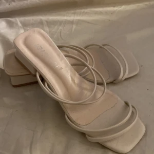 Beiga sandaler med smala remmar - Snygga beiga sandaler från NA-KD med smala remmar och fyrkantig tå. Skorna har låg klack och platt sula, perfekt för en trendig look. Tillverkade i syntetmaterial och passar perfekt till sommarens outfits.