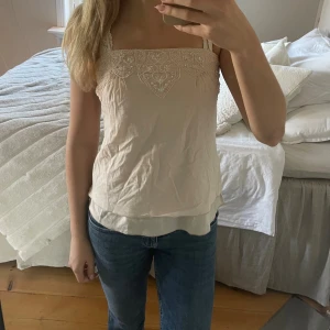Beige linnetopp  - Supersöt beige linnetopp från Plains & Prints i storlek XS. Toppen har tunna axelband, dubbla lager tyg och ett detaljerat broderi framtill med pärlor och paljetter. Smockad rygg för skön passform. 