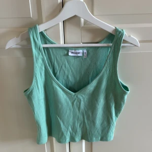 Mintgrön ribbad linnetopp från Weekday - Säljer en mintgrön ribbad linnetopp från Weekday. Toppen är croppad med v-ringning framtill och breda axelband. Tillverkad i mjuk bomullsmix, perfekt för varma dagar. Enkel och stilren design som är lätt att matcha. I fint skick. Storlek M. Tvättlappen är avklippt.
