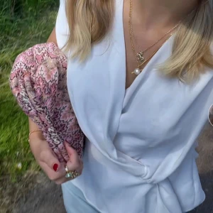Vit topp - Säljer en superfin vit topp som är perfekt för sommardagar. Den har en elegant v-ringning och knytning i midjan för en smickrande passform. Perfekt för både vardag och fest! 🌸