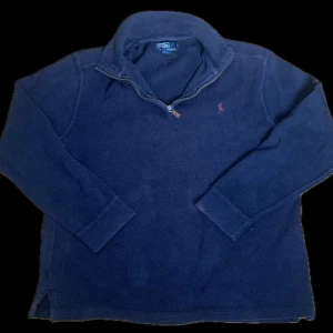 Blå polo quarter zip - Klassisk quarterzip-tröja från Polo Ralph Lauren i mörkblå färg. Röd broderad logo på bröstet. Bekväm och tidlös modell som funkar både till vardag och lite mer uppklätt.  ✔ Storlek: L ✔ Färg: Mörkblå med röd logo ✔ Passform: Regular fit ✔ Material: Bomull (stickad) ✔ Skick: Mycket bra – inga hål, fläckar eller tydligt slitage  Nypris: ca 1 000–2 000 kr Mitt pris: 399 kr  Hör av er vid minsta fråga!🤩