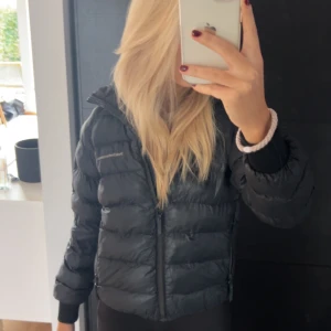 Svart dunjacka från Peak Performance - Säljer en svart dunjacka från Peak Performance med huva och dragkedja framtill. Jackan är i bra skick och har en clean look med diskret logga på bröstet. Perfekt för kyliga dagar och enkel att matcha med allt. Snygg och funktionell för höst och vinter.priset är diskuterbart vid snabbt köp.💞strl 150( sitter lite kortare på mig som är 167cm)