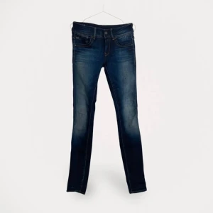 Mörkblå skinny jeans från G-Star RAW - Snygga mörkblå skinny jeans från G-Star RAW med klassisk femficksdesign och coola slitningar.  Storlek: 27/34 Material: Bomull 99%/Elastan 1% Färg: Blå Använd, men utan anmärkning.