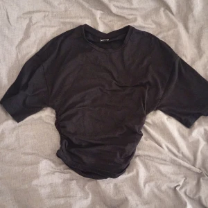 Svart t-shirt med snörning i sidan - Svart t-shirt från Gina Tricot med korta ärmar och cool snörningsdetalj i sidan som ger en snygg och unik look. Materialet är mjuk bomull och passformen är normal. Perfekt för dig som gillar stilrena plagg med en twist.