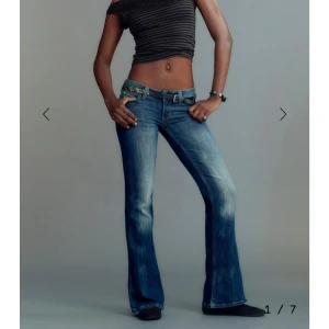 Blå bootcut jeans låg midja - Snygga blå bootcut jeans med låg midja och slitna detaljer på låren. Endast använda en gång. Jeansen har klassisk femficksdesign och är tillverkade i denim med en cool tvätt. Perfekta för dig som gillar en avslappnad och trendig look.