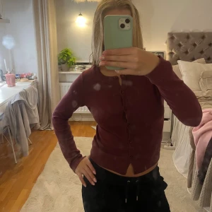 Vinröd kofta från H&M med knappar - Mysig vinröd kofta från H&M med rund halsringning och knappar hela vägen framtill.