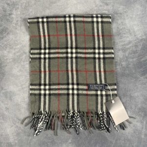 Burberry halsduk - Skick: 7/10 (Vintage), begagnad, inga defekter. | Vad som ingår: Endast halsduken. | Ordinarie pris: +- 4000 SEK / 400 €. | OBS: Halsdukarna finns i samma färgsättning men kan skilja sig något i modell eller detaljer, beroende på tillverkningsår eller kollektion.