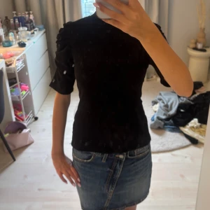 Svart topp med puffärm - Säljer en svart topp med puffade axlar och halvlånga ärmar. Toppen har en figurnära passform och hög hals, vilket ger en stilren och trendig look. Perfekt att styla med jeanskjol eller byxor.
